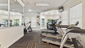 Un gimnasio con cintas de correr, bicicletas estáticas y un espejo grande.