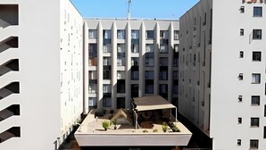 En moderne bygning med en central gårdsplads, flere balkoner og et fladt tag med et lille haveområde.