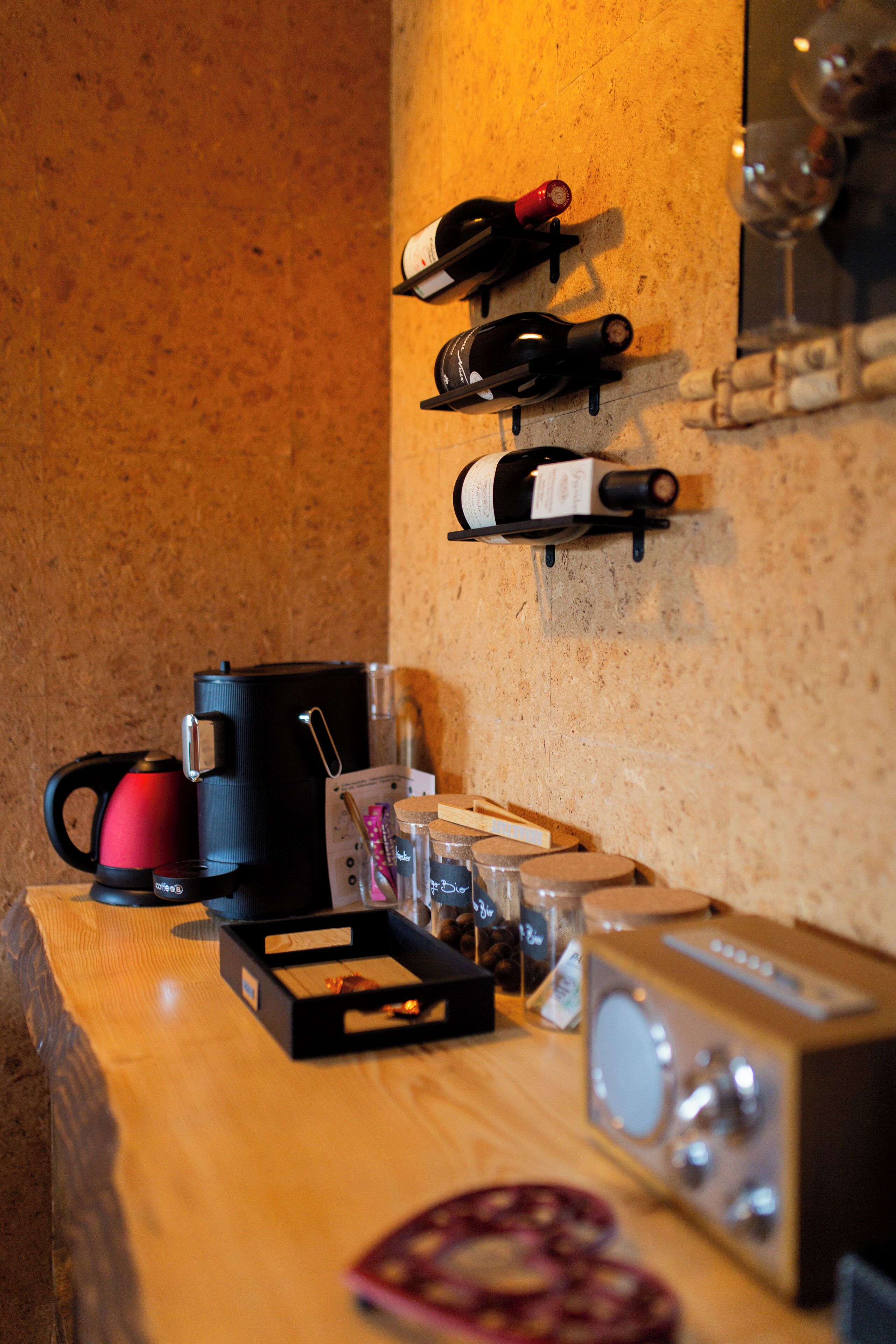 A kitchen counter with a coffee maker, wine bottles, corks, and a radio.