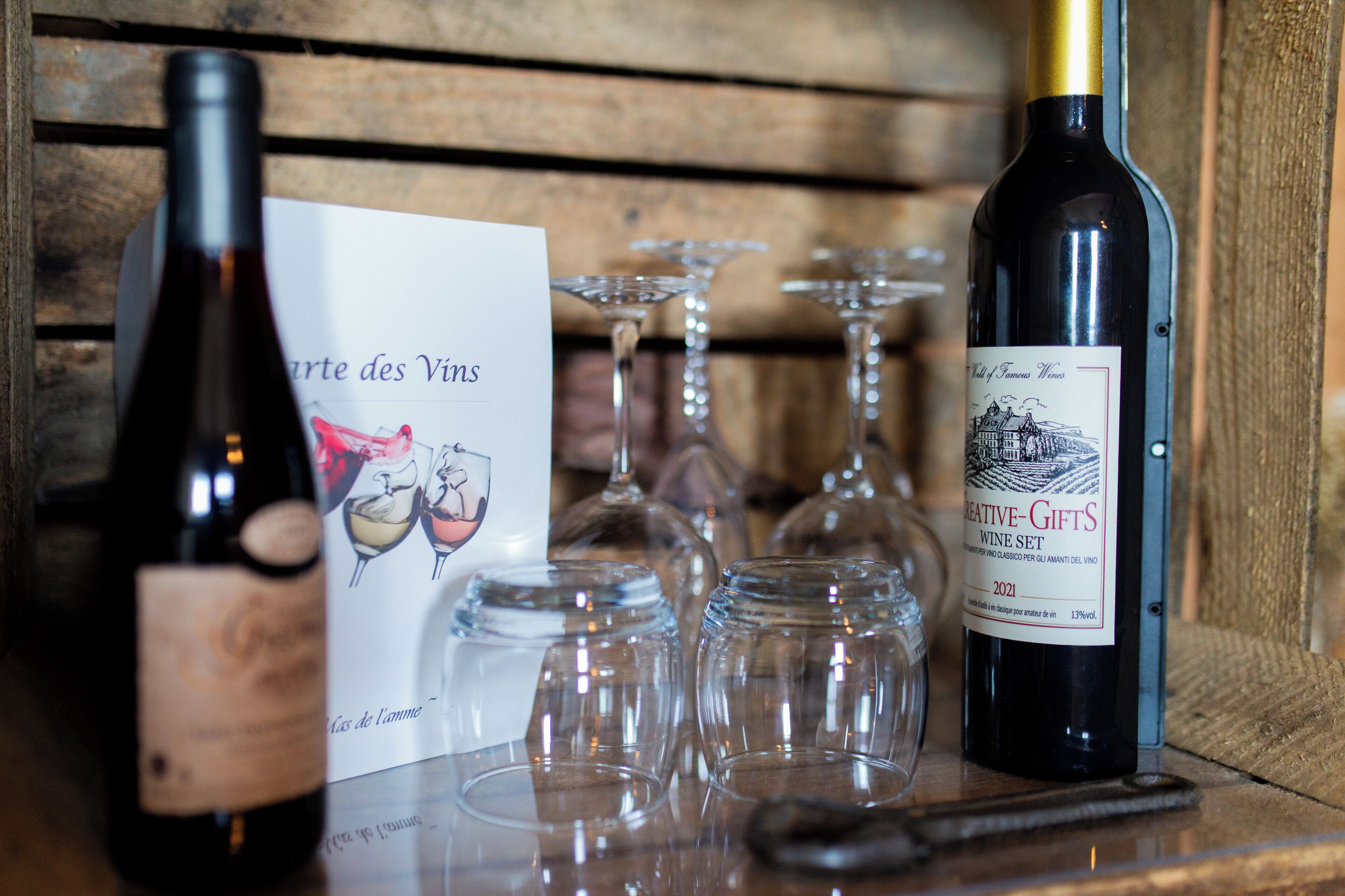 A wine bottle, a wine glass set, and a menu on a wooden table.