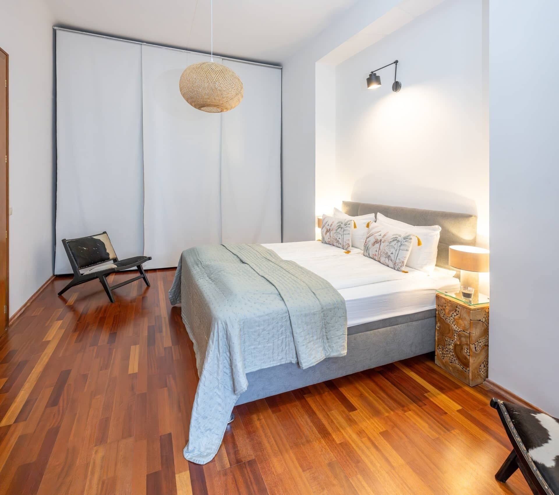 A bedroom with a bed, a chair, a lamp, and a hanging light fixture.