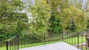 Un espace extérieur clos, doté d’une surface pavée et entouré d’arbres et de verdure.