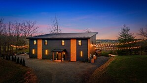 A modern house with a dark exterior, a wooden door, and a small porch.
