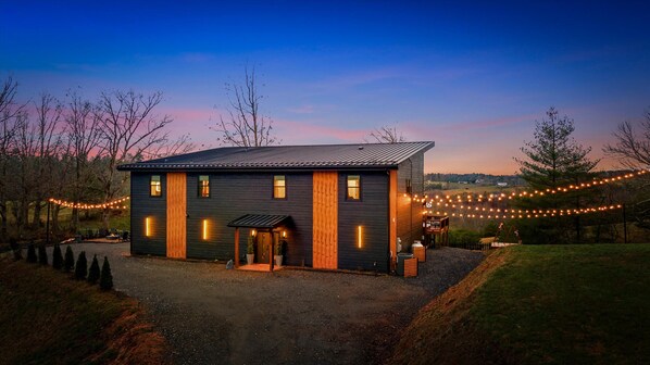 A modern house with a dark exterior, a wooden door, and a small porch. - Asheville Speakeasy • Heated Pool + Hot Tub • Sauna • Game Room • Sleeps 20 (Weaverville)