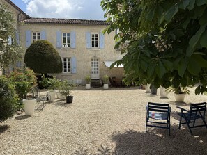 A courtyard with a building, potted plants, and outdoor furniture. - Charentaise cottage - private swimming pool (Saint-Palais-du-Né)