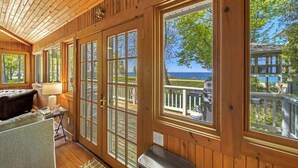 Ein Zimmer mit Holzwänden, großen Fenstern, einer hölzernen Bank und einem Tisch.