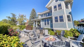 A two-story house with a porch, outdoor seating, and a fire pit. - Lakefront | South Beach | 6BR (South Haven)