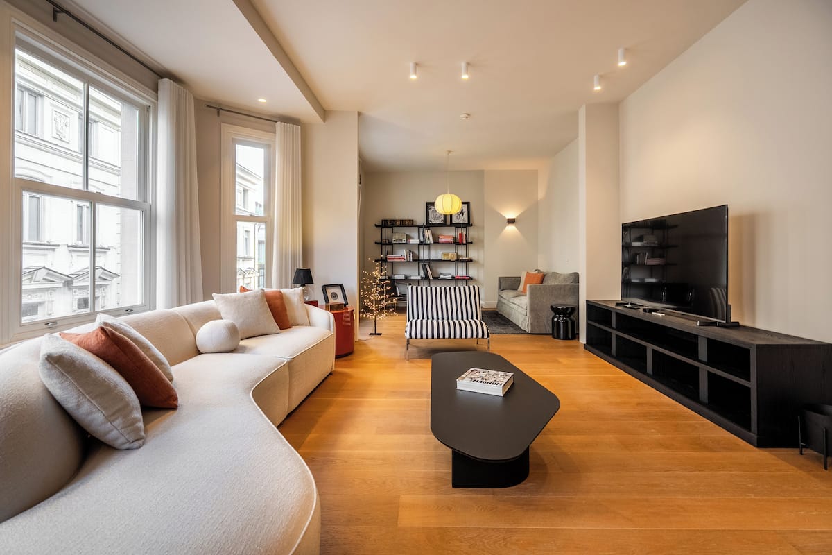A modern living room with a sofa, a coffee table, a TV stand, and a bookshelf.