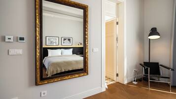 A bedroom with a large mirror, a bed, a black chair, and a floor lamp.