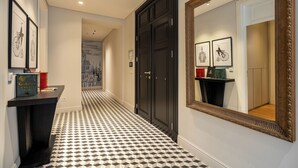 A hallway with a black and white checkered floor, a black door, and framed artwork on the walls. - The Muradiye Luxury Apartments (Istanbul)