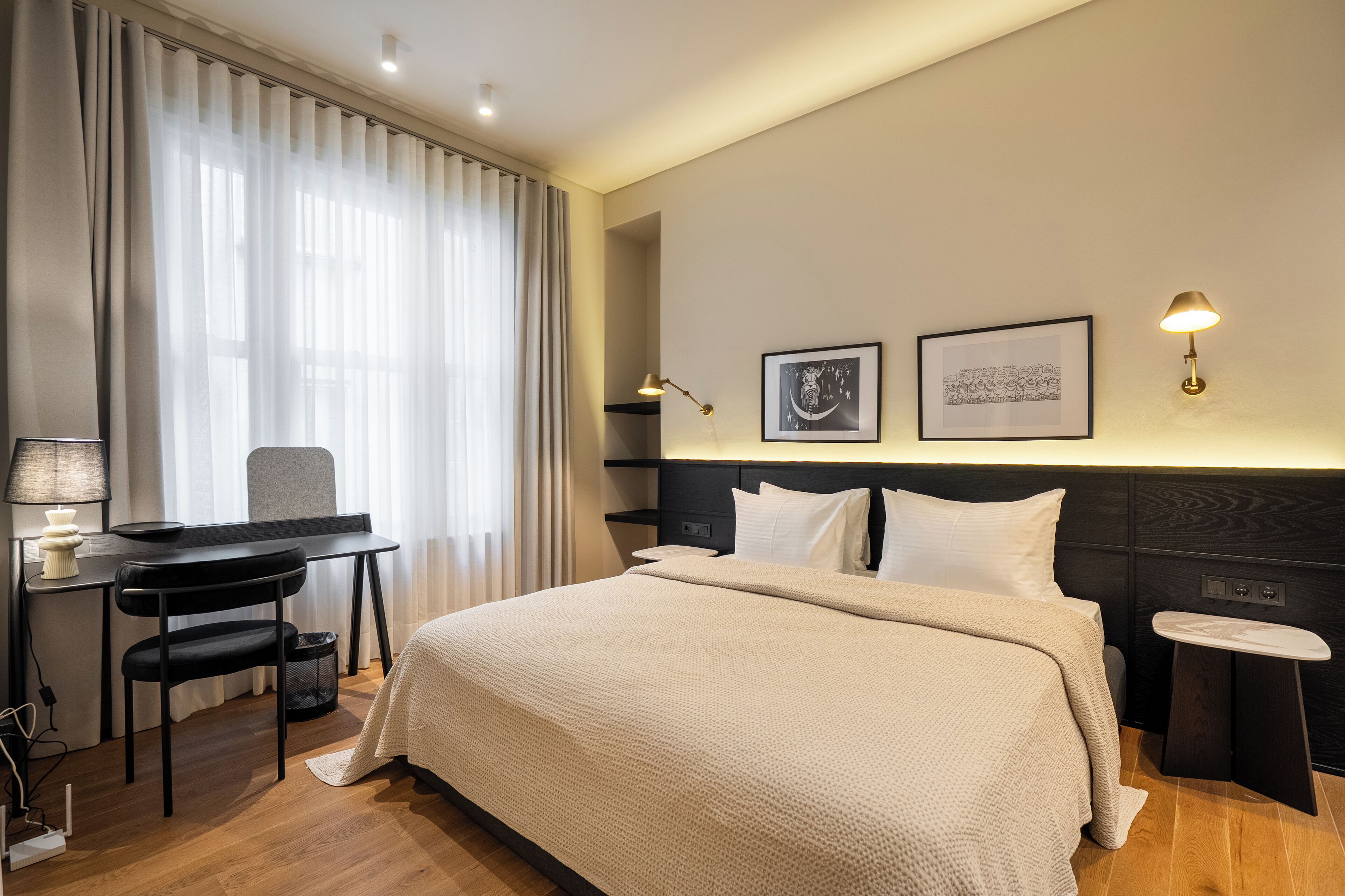 Een hotelkamer met een bed, bureau, stoel en twee wandlampen.