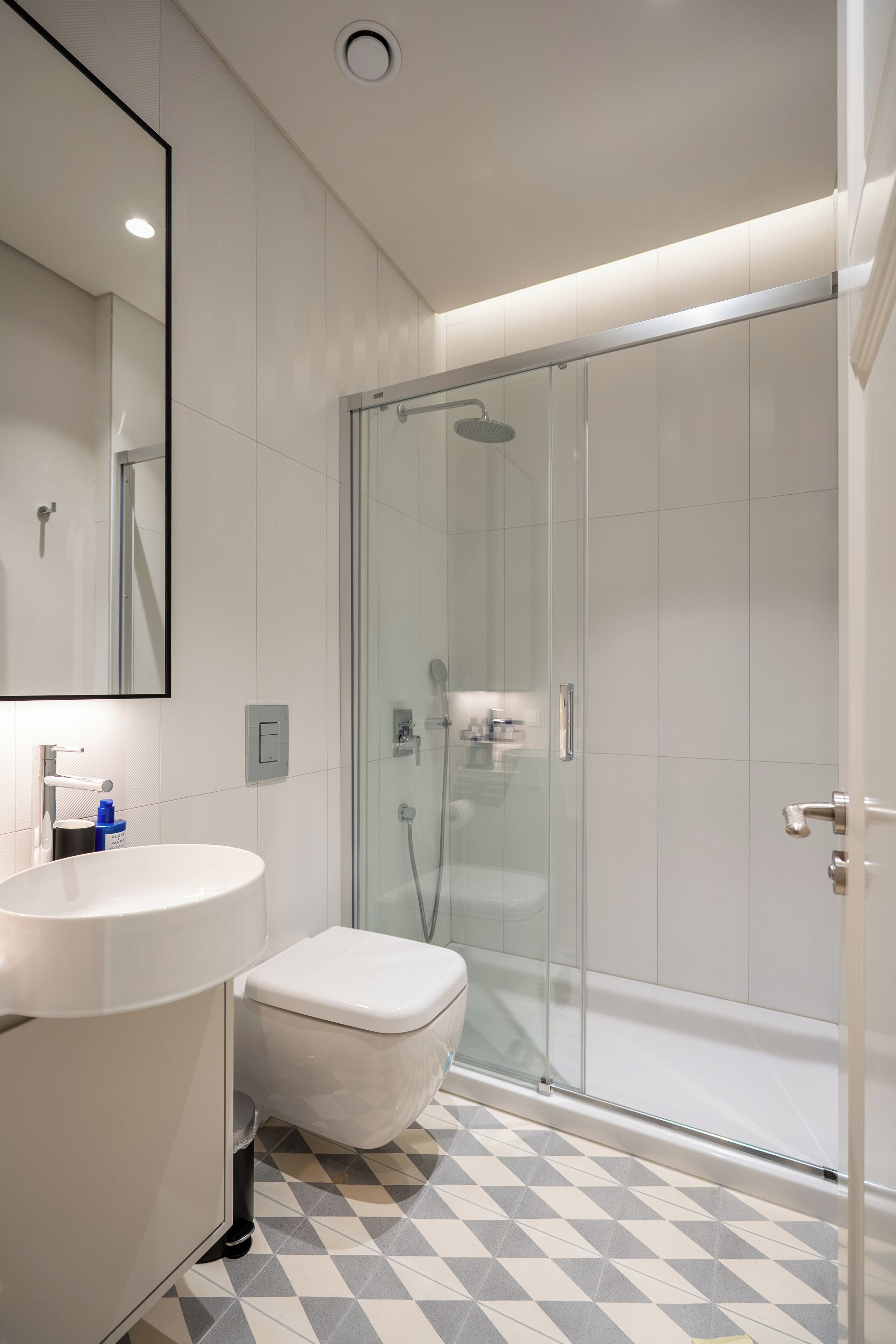 A modern bathroom with a glass-enclosed shower, a white sink, and a toilet.