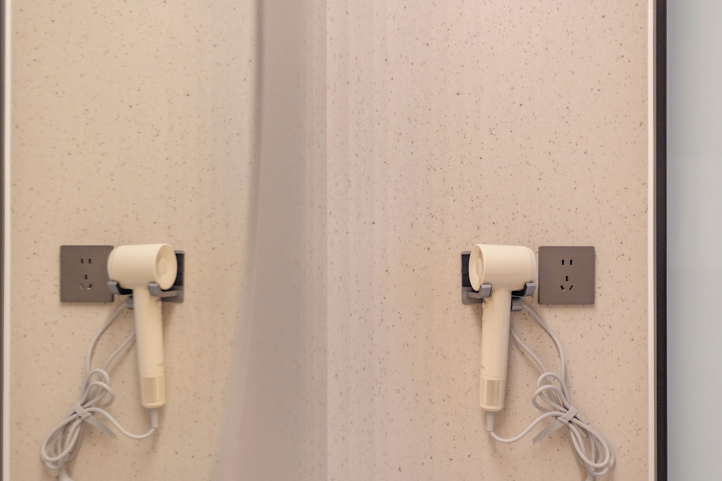 Twee haardrogerhouders zijn aan een muur bevestigd met stopcontacten.