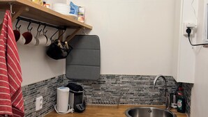Una cocina compacta con encimera de madera, un lavamanos de acero inoxidable y salpicadero de azulejos.