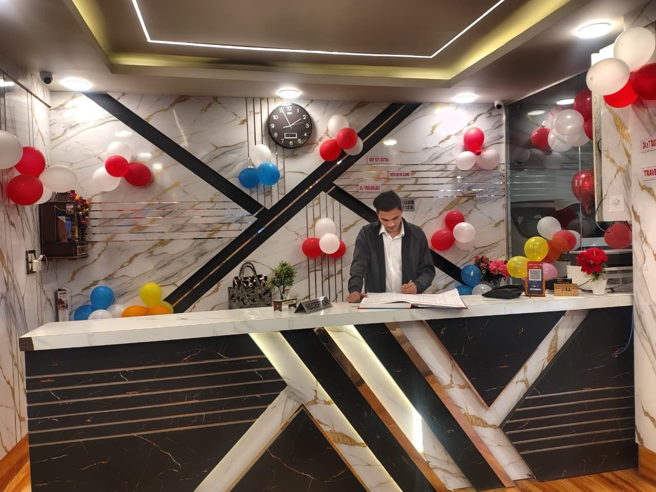 A reception desk with a marble and black design, surrounded by colorful balloons.
