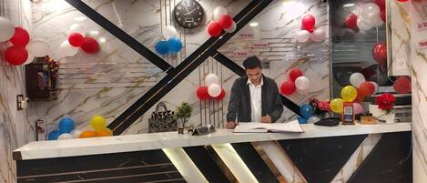 A reception desk with a marble and black design, surrounded by colorful balloons.