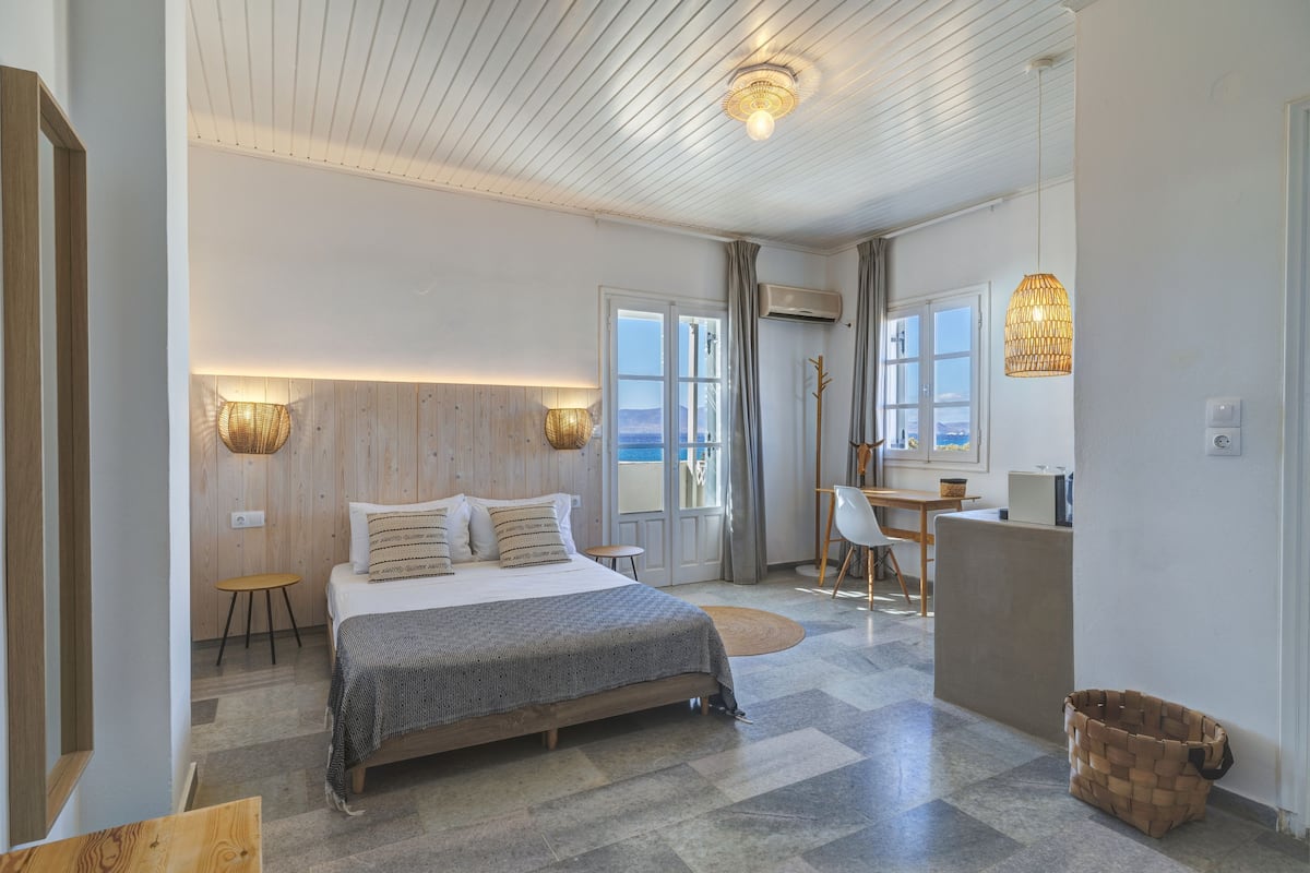 A modern bedroom with a bed, bedside tables, a desk, and a view of the outdoors.
