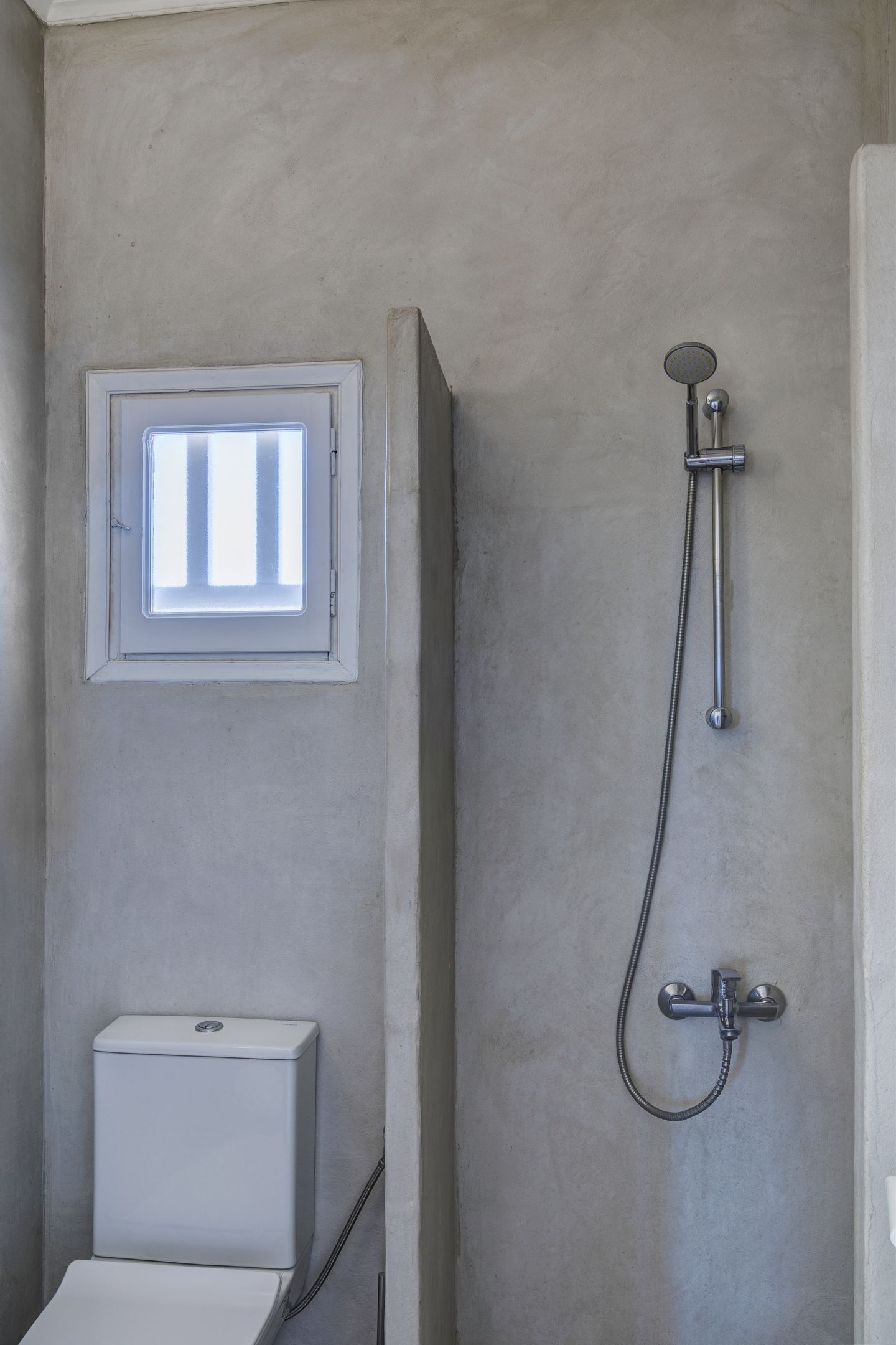 Un bagno con il water, una finestra e una doccia.