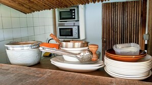 Un taulell de cuina amb plats apilats, un colador i una olla.