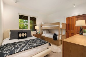 A bedroom with a large bed, a smaller bed, a desk, and a wardrobe.