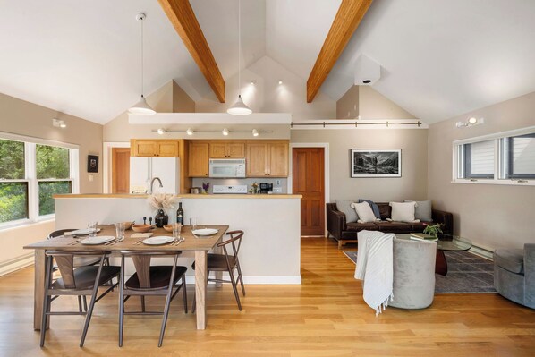 A spacious living area with a wooden dining table, a sofa, and a coffee table.