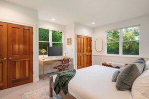 A bedroom with a bed, a desk, a chair, and two windows.