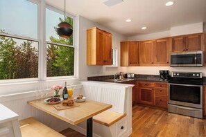 A modern kitchen with wooden cabinets, stainless steel appliances, and a breakfast setup on the counter.