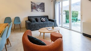 Ein Wohnzimmer mit einer Couch, Sesseln, einem Couchtisch und einem Essbereich mit Stühlen und Tisch.