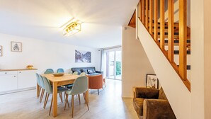Ein moderner Wohnbereich mit Essbereich, einer Couch und einer Treppe.