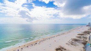 Una playa con arena, cielo despejado y mar tranquilo.
