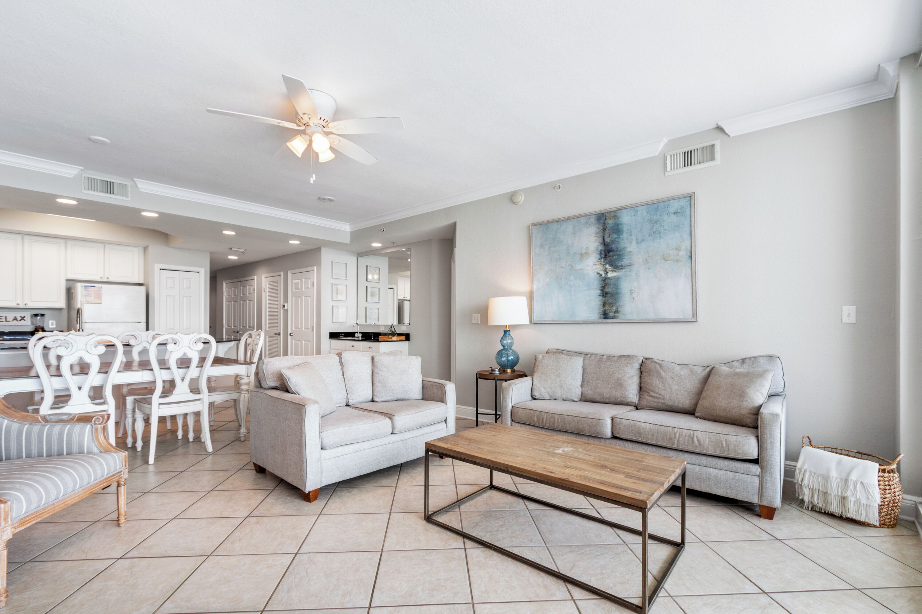A spacious living area with a dining set, two sofas, a coffee table, and a ceiling fan.