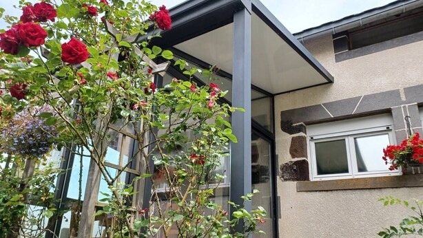 Una casa moderna con fachada de vidrio, pared de piedra y ventana con planta colgante.