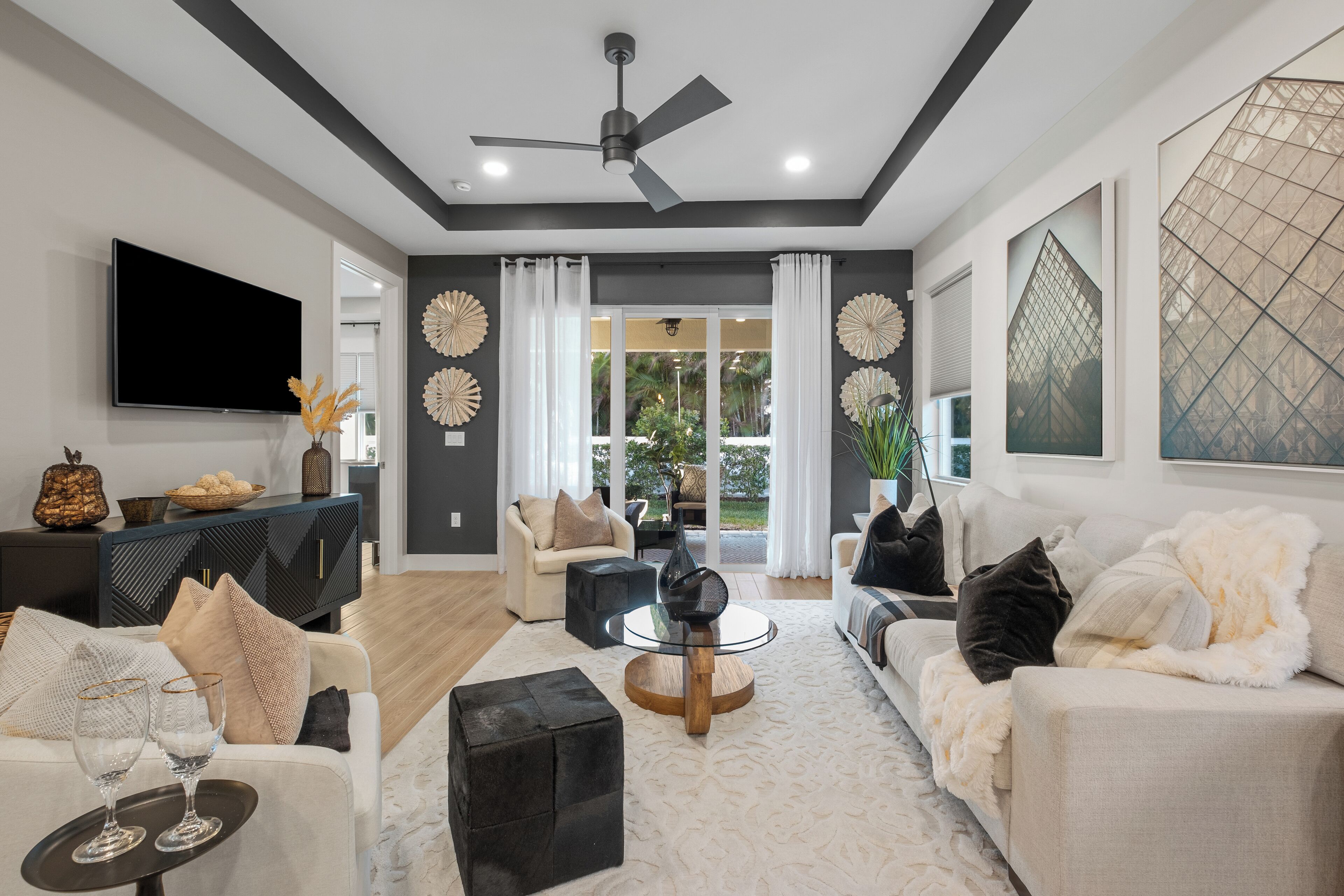 Sink into plush white sofas in your sophisticated living room, where modern design meets comfort beneath elegant tray ceilings and natural light.