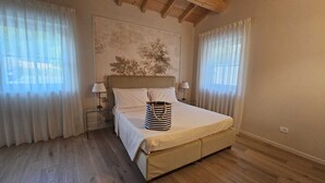 A bedroom with a bed, two bedside tables, a lamp on each table, and a window with curtains. - Relax and Comfort in an Elegant Venetian Villa with a Beautiful Outdoor Pool (Tregnago)