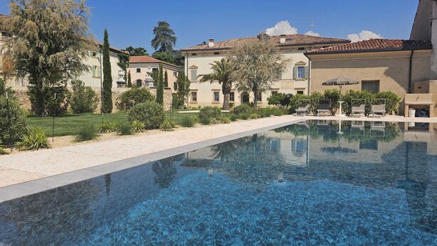 A swimming pool with clear blue water, surrounded by a landscaped garden with various plants and trees. - Relax and Comfort in an Elegant Venetian Villa with a Beautiful Outdoor Pool (Tregnago)