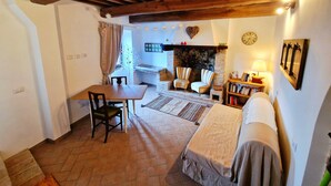 Ein gemütliches Zimmer mit Kamin, Esstisch und zwei Sesseln.