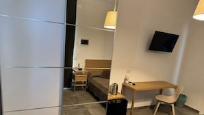 A modern hotel room with a bed, a desk, a chair, a TV, and a suitcase.