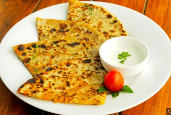 A plate of flatbreads with a side of yogurt and a cherry tomato.