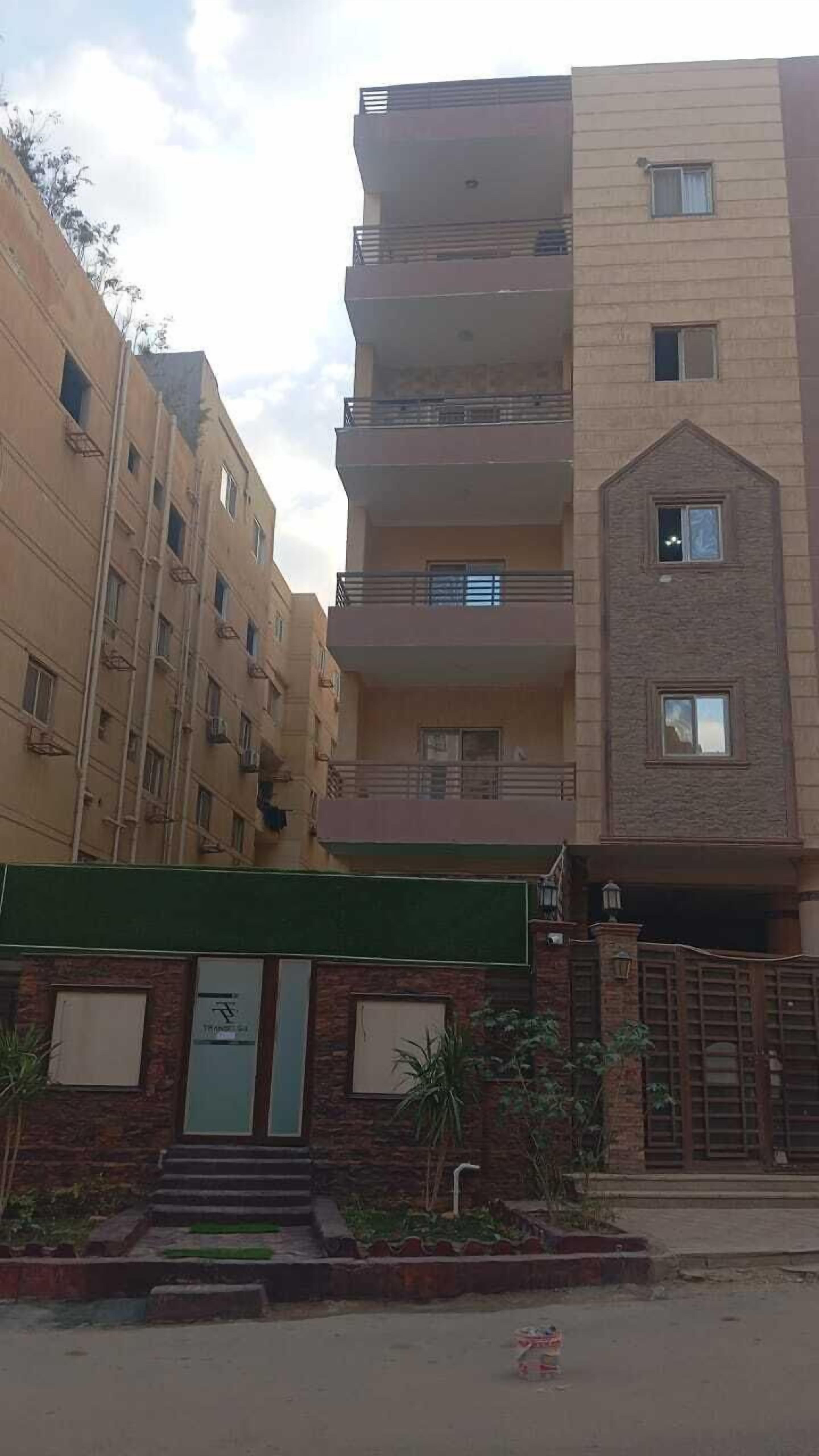 A multi-story residential building with balconies and a gated entrance.