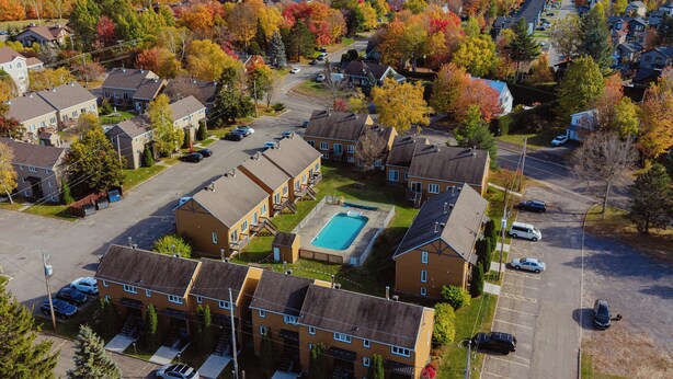 Vue aérienne d’un quartier résidentiel avec des maisons, une piscine et un parking.