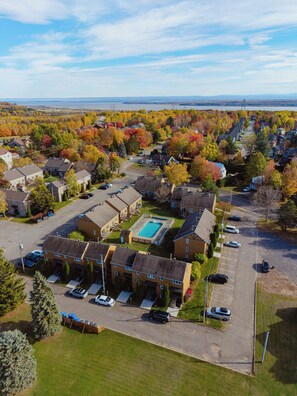 An aerial view of a residential area with houses, a swimming pool, and a parking lot. - BELANSKI | Luxury Condo - Price per Season (Beaupré)