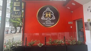 Hotel La Trinidads facade med et tydeligt logo og rød farve.