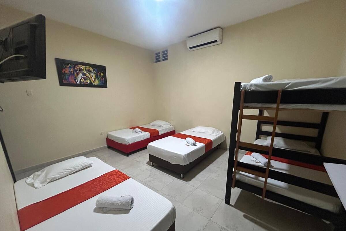 Un dormitorio con literas, dos camas individuales y un cuadro en la pared.