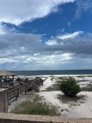 A beach with a wooden boardwalk, a thatched-roof structure, and a sandy area with sparse vegetation. - New 2BR Home in Perdido Key; Pet-Friendly Fenced Yard; Near Beach & Florabama (Pensacola)