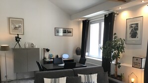 Un soggiorno moderno con un divano grigio, un tavolo da pranzo e un'ampia finestra con tende.