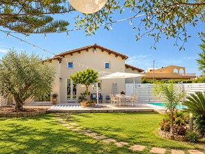 Une maison à deux étages dotée d’une terrasse, d’un espace salon extérieur et d’une piscine.