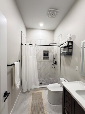 A modern bathroom with a shower, toilet, and sink.