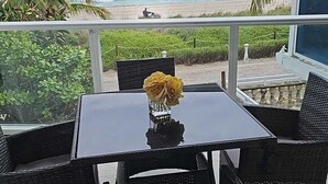 A patio with a table and chairs, overlooking a beach and ocean. - Biggest Oceanfront Apartment with Terrance Beach Acess and Parking (Miami Beach)