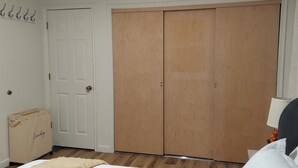 Una camera da letto con un armadio in legno, una porta bianca e una borsa piccola sul pavimento.