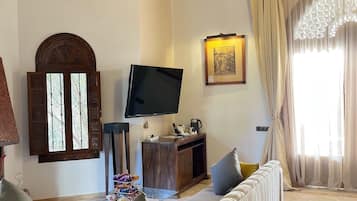 Suite Deluxe, vista a la alberca | Área de sala de estar | Televisión de pantalla plana